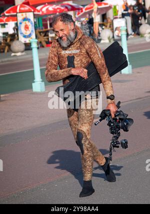 Ein Taucher geht zum Meer, um in Brighton zu schwimmen Stockfoto
