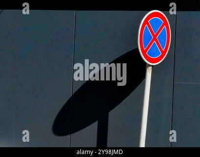 Kein Halt: Rundes Verkehrsschild mit Blau und Rot vor einer grauen Mauer Stockfoto