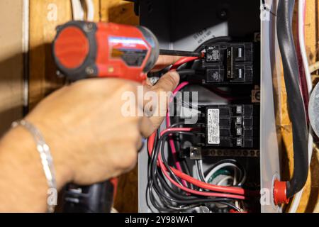 Der Elektriker installiert mit einer Bohrmaschine einen neuen Leistungsschalter in einer elektrischen Schalttafel für Wohnzwecke. Selektiver Fokus Stockfoto