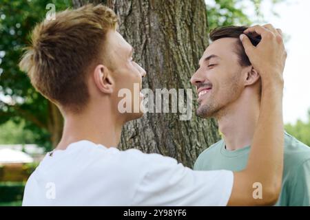 Zwei fröhliche Männer umarmen sich, während sie ein herzliches Lächeln in einer lebhaften Outdoor-Umgebung teilen. Stockfoto