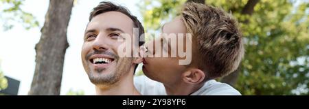 Ein fröhliches Paar genießt die Gesellschaft, während es einen zarten Kuss in einem sonnigen Park teilt. Stockfoto