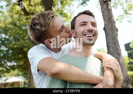 Ein Paar teilt eine zärtliche Umarmung, lacht zusammen und genießt einen warmen Tag in der Natur. Stockfoto