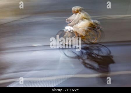 Kreatives Schwenkfoto, das die dynamische Bewegung eines Radfahrers bei Nacht durch die Straßen der Stadt aufnimmt und Geschwindigkeit und Bewegung hervorhebt. Stockfoto