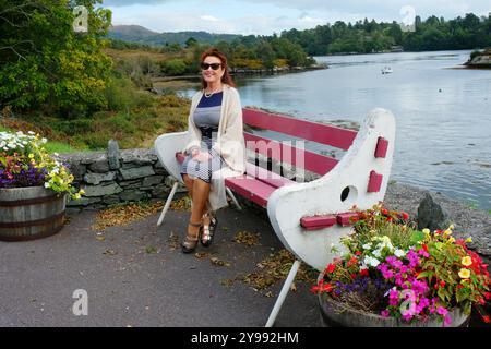Attraktive reife Frau, sitzend, lächelnd in die Kamera Stockfoto