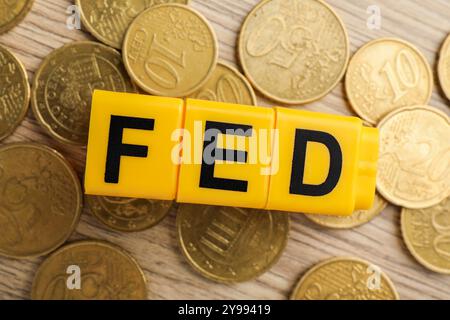 Würfel mit den Buchstaben Fed (Federal Reserve System) und Münzen auf Holztisch, flach gelegt Stockfoto