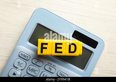 Würfel mit den Buchstaben Fed (Federal Reserve System) und Taschenrechner auf weißem Holztisch, Draufsicht Stockfoto