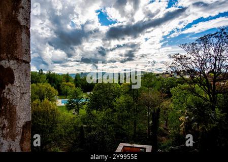 Blick auf eine mittelalterliche Burg in Italien mit dem blauen Himmel, den zinnenverkleideten Ziegelwänden, der Sonne gegen das Licht und den Wald Stockfoto