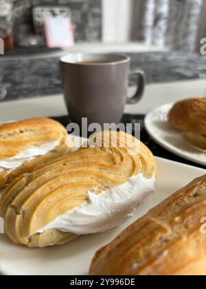 Hausgemachte Eclairs auf einem Teller. Eine Tasse Kaffee in der Nähe. Nahaufnahme. Stockfoto