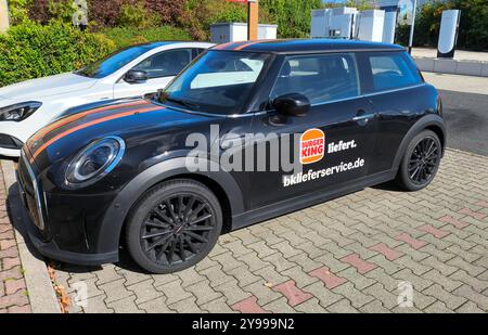 REKORDDATUM NICHT ANGEGEBEN Bayern, Deutschland - 1. Oktober 2024: Ein schwarzer Mini Cooper mit Burger King Delivery Service Branding steht geparkt auf einem Parkplatz vom Fastfood Schnellrestaurant Burgerking *** ein schwarzer Mini Cooper mit Burger King-Lieferservice-Branding steht geparkt auf einem Parkplatz vom Fastfood Schnellrestaurant Burgerking Stockfoto