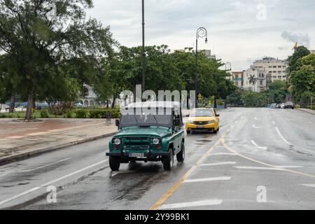 HAVANNA, KUBA - 28. AUGUST 2023: Grün restaurierter UAZ-469 Geländewagen und gelbes Taxi in den Straßen von Havanna, Kuba nach Regen Stockfoto