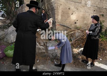 Kapparot, Ultra-orthodoxer Mann, schwingt einen Hahn über den Kopf seines Kämmers, während sie betet, für ihre Sünden zu büßen, bevor Jom Kippur, Mutter und Geschwister schauen. Stockfoto