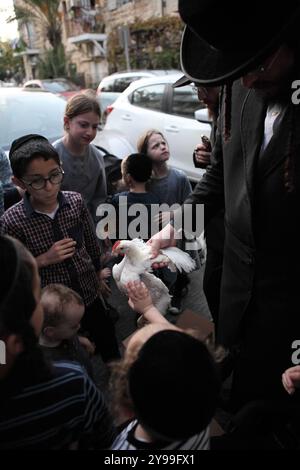 Ultra Orthodox man zeigt Kindern und Kleinkindern einen Hahn, der ihn ansieht und anfasst, bevor er für Kapprot getötet wird, kurz vor Yom Kippur oder dem Tag der Sühne. Stockfoto