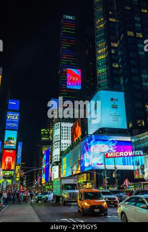 Nächtlicher Blick auf den Times Square mit hell beleuchteten Reklametafeln für LG, TSX und verschiedenen Anzeigen entlang der belebten Straße mit Autos und Menschen. New York. USA. Stockfoto