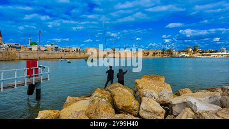 Blick auf die Skyline und die Festung der Altstadt von Akko. Im Vordergrund fischen Männer, Israel, Naher Osten Stockfoto