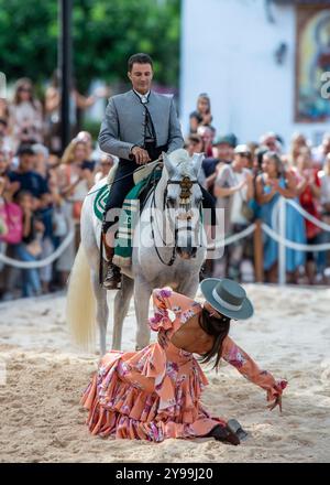 Fuengirola, Malaga, Spanien. Reiter und Tänzer in rosa Flamenco-Kleid und Hut, die während der Messe eine Nachbildung eines Sevillanentanzes vorführen Stockfoto