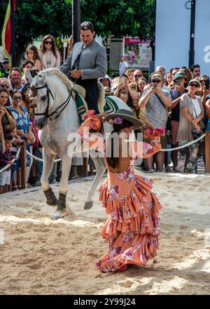 Fuengirola, Malaga, Spanien. Reiter und Tänzer in rosa Flamenco-Kleid und Hut, die während der Messe eine Nachbildung eines Sevillanentanzes vorführen Stockfoto