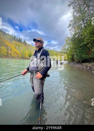 Angler Steelhead Angeln im malerischen Bulkley Valley, British Columbia, in einem Fluss, umgeben von Herbstlaub und bergigem Gelände Stockfoto