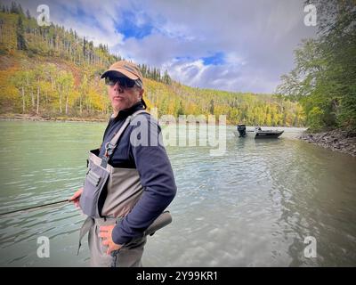 Angler Steelhead Angeln im malerischen Bulkley Valley, British Columbia, in einem Fluss, umgeben von Herbstlaub und bergigem Gelände Stockfoto