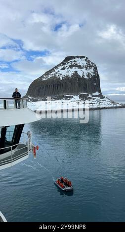 Passagiere an Bord der Lindblad Nat Geo Endurance beobachten ein kleines Expeditionsboot, das durch die ruhigen Gewässer in der Nähe des Edinburgh Rock in der Antarktis fährt Stockfoto