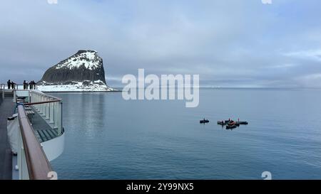 Passagiere an Bord der Lindblad Nat Geo Endurance beobachten den Edinburgh Rock in der Antarktis, während kleine Expeditionsboote die ruhigen Gewässer darunter erkunden Stockfoto