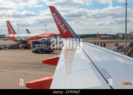 EasyJet-Flugzeuge am Flughafen London Gatwick, Großbritannien, mit Fluggästen, die aus- und zum Terminal laufen. EasyJet-Betriebsbasis mit basierten Jets Stockfoto