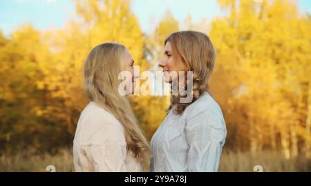 Porträt von glücklichen zwei Frauen, lächelnder reifer Mutter und erwachsener Tochter, die sich im Herbstpark umarmt Stockfoto