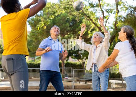 Fröhliche multirassische Gruppe von erwachsenen Menschen spielen Volleyball-Spiel im Freien Stockfoto
