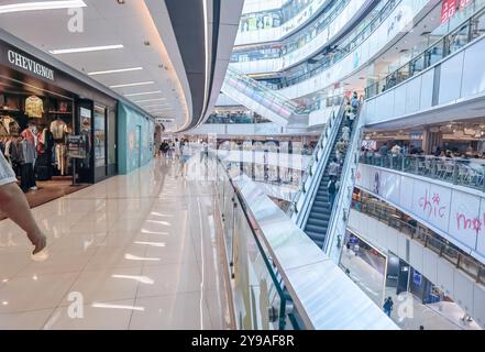 Hongkong, China, 08. Oktober 2024: Innenraum eines Einkaufszentrums mit Rolltreppen, Geschäften und Menschen zu Fuß. Stockfoto