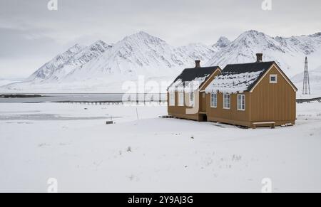 Ockerfarbene Häuser, Forschungssiedlung, wissenschaftliche Siedlung, winterliche Berglandschaft, NY-Alesund, Kongsfjord, Spitzbergen, Svalbard an Stockfoto