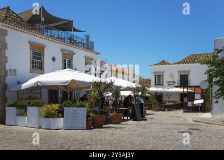 Straßencafé mit Sonnenschirmen und Pflanzen in einer malerischen, sonnigen Kopfsteinpflastergegend, Vila Adentro, Villa, Praca Dom Afonso III, Faro, Algarve, Portugal, Europ Stockfoto