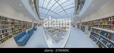 Galeriesaaal, moderne Bibliothek mit Glasdach und weißer Treppe, umgeben von Bücherregalen in einem hellen offenen Raum, öffentliche Bibliothek am Mailaender Platz, e Stockfoto