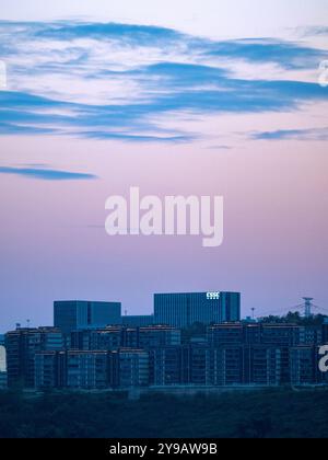 Blick auf die Stadt Chongqing bei Sonnenuntergang, Hochhäuser auf Hügeln und Berge im Hintergrund, Wolken im Sonnenuntergang rosa beleuchtet. Stockfoto