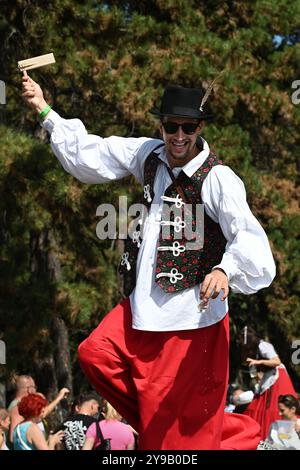 Badacsony, Balaton, Ungarn - 8. September 2024: Straßenparade des Weinerntefestes, Mann auf Stelzen mit einer hölzernen Spinnratsche Stockfoto