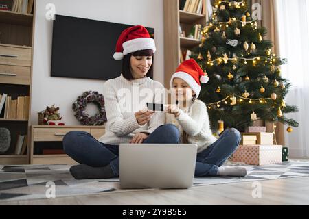 Mutter und Tochter kaufen während der Weihnachtszeit zu Hause online Stockfoto