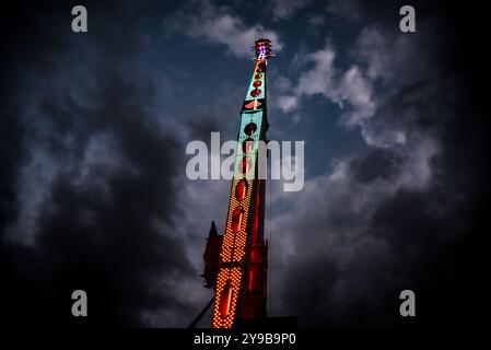 Aufragende Vergnügungsfahrt, beleuchtet von Neonlichtern auf dem Pariser Jahrmarkt Stockfoto