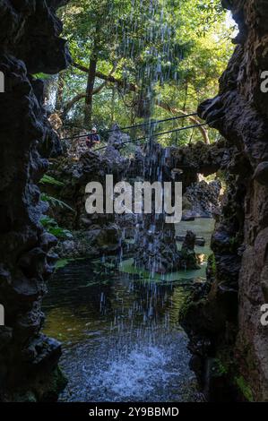 Sintra, Portugal - 9. September 2024 : der friedliche Wasserfall fließt sanft in einen ruhigen Teich, eingerahmt von lebhaftem Laub. Stockfoto