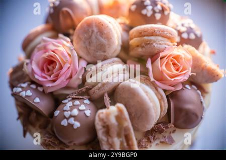 Nahaufnahme eines köstlichen Tortes, dekoriert mit Makronen, Schokolade und Rosen, bereit, während einer Party serviert zu werden Stockfoto