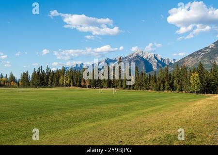 Three Sisters Sports Complex, Mehrzweckfeld und Spielplatz. Canmore, Alberta, Kanada. Die kanadischen Rockies überragen den blauen Himmel im Hintergrund. Stockfoto