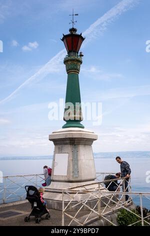 Touristen rund um den Leuchtturm am Ufer des Lemansees mit dem Leuchtturm in Evian les Bains in den Alpen in der Haute-Savoie Stockfoto