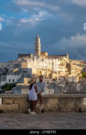 In der malerischen Stadt Matera Italien genießt ein Paar einen ruhigen Moment mit Blick auf alte Steinhäuser, während die Sonne untergeht und ein warmes Leuchten über die bezaubernde Landschaft wirft. Stockfoto
