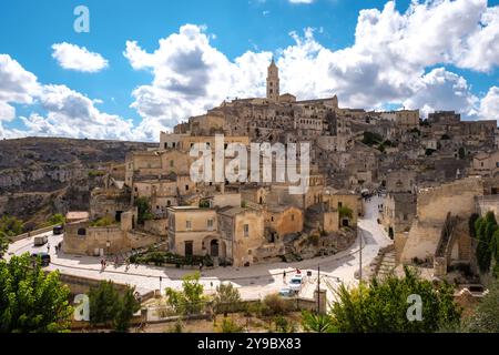 Eingebettet in die Hügel, zeigt Matera seine atemberaubenden Steinbauten und verwinkelten Gassen vor dem Hintergrund dramatischer Wolken und blauer Himmel. Erleben Sie den Charme und die Geschichte dieser antiken Stadt. Stockfoto