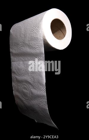 Eine einzelne Rolle weißes Toilettenpapier mit geprägtem Design ist auf schwarzem Hintergrund fotografiert. Stockfoto