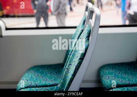 Innenraum eines Stadtbusses ohne Fahrgäste. Ein Bus mit Sitzplätzen in der Nähe des Fensters. Beförderung von Passagieren. Das Konzept des Busverkehrs. Stockfoto