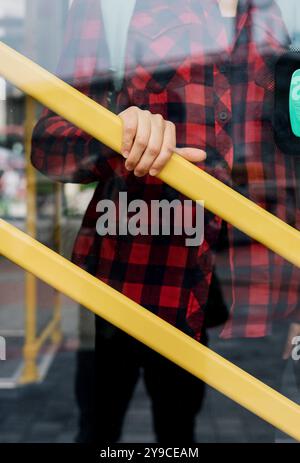 Weibliche Hand, die aus Sicherheitsgründen einen Metallhandlauf in öffentlichen Verkehrsmitteln hält. Stockfoto