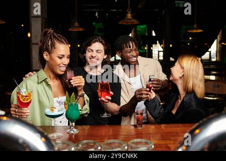 Begeisterte Kollegen stoßen mit bunten Cocktails an und genießen gemeinsam eine fröhliche Atmosphäre. Stockfoto