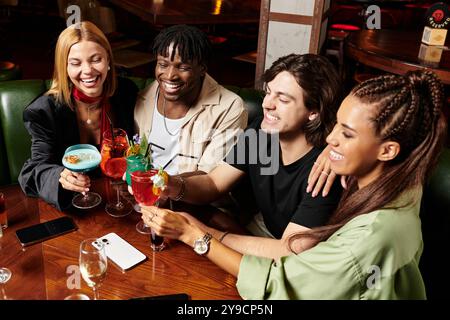 Junge Profis stoßen bei einer lebhaften Firmenfeier freudig mit bunten Cocktails an. Stockfoto