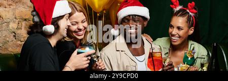 Junge Profis teilen Lächeln und trinken bei einem lebhaften Feiertagstreffen und genießen die Atmosphäre. Stockfoto