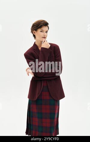 Eine Frau posiert anmutig drinnen, elegant gekleidet in raffinierter Winterkleidung. Stockfoto