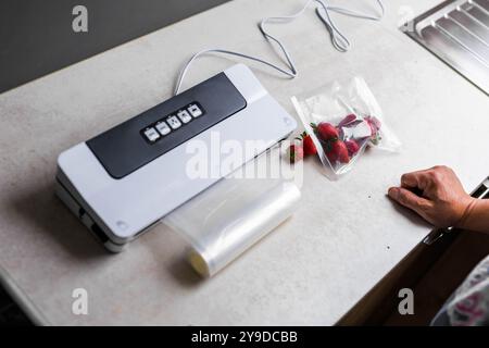 Die Hand eines Mannes benutzt eine Vakuummaschine, um Erdbeeren in Plastiktüten zu saugen. . Hochwertige Fotos Stockfoto