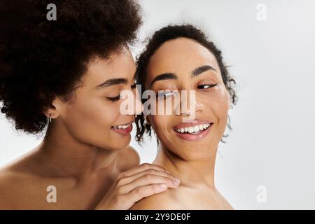 Zwei lächelnde Frauen genießen eine enge Verbindung und strahlen Freude und Selbstvertrauen in einer lebendigen Atmosphäre aus. Stockfoto